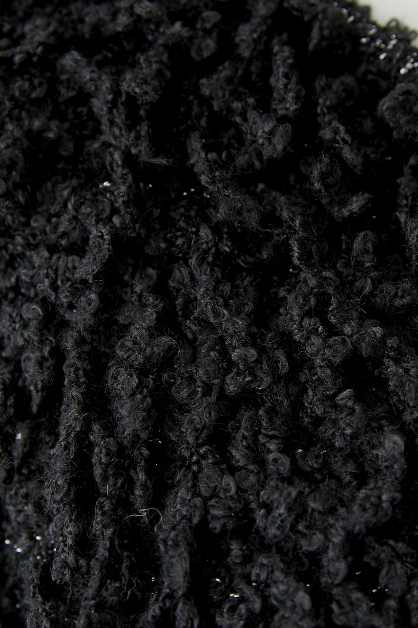 Schwarze Strickjacke: Detailaufnahme des flauschigen, strukturierten Materials ohne sichtbares Model.