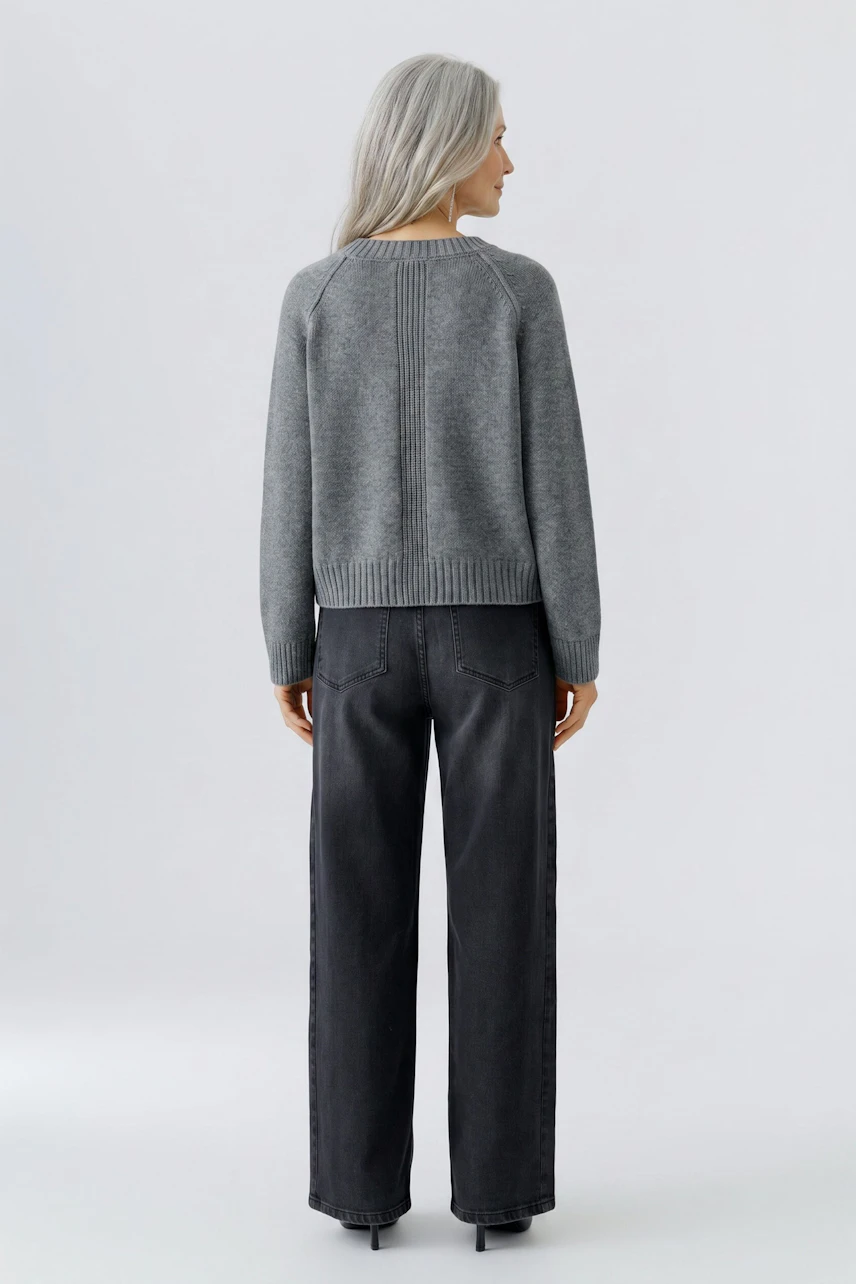 Grauer Damen-Pullover: Frau von hinten im lässigen Strickpullover und dunkler Jeans.