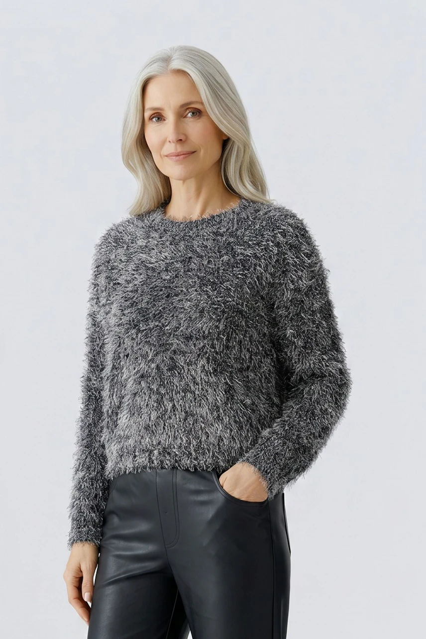 Frau im grauen, flauschigen Pullover, kombiniert mit schwarzer Hose. Lässiger Look für jeden Tag.
