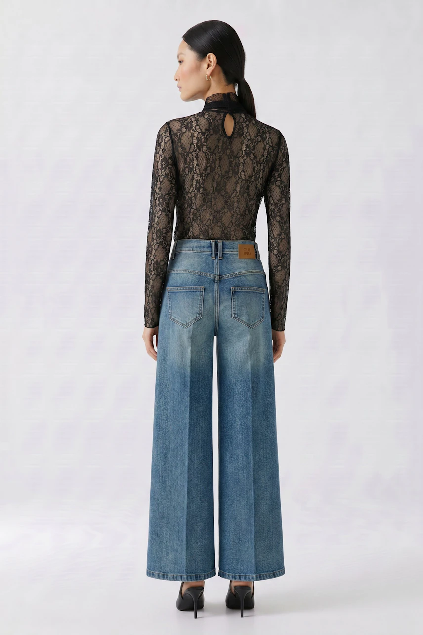 Woman in lace long-sleeve shirt and wide-leg jeans, viewed from the back.