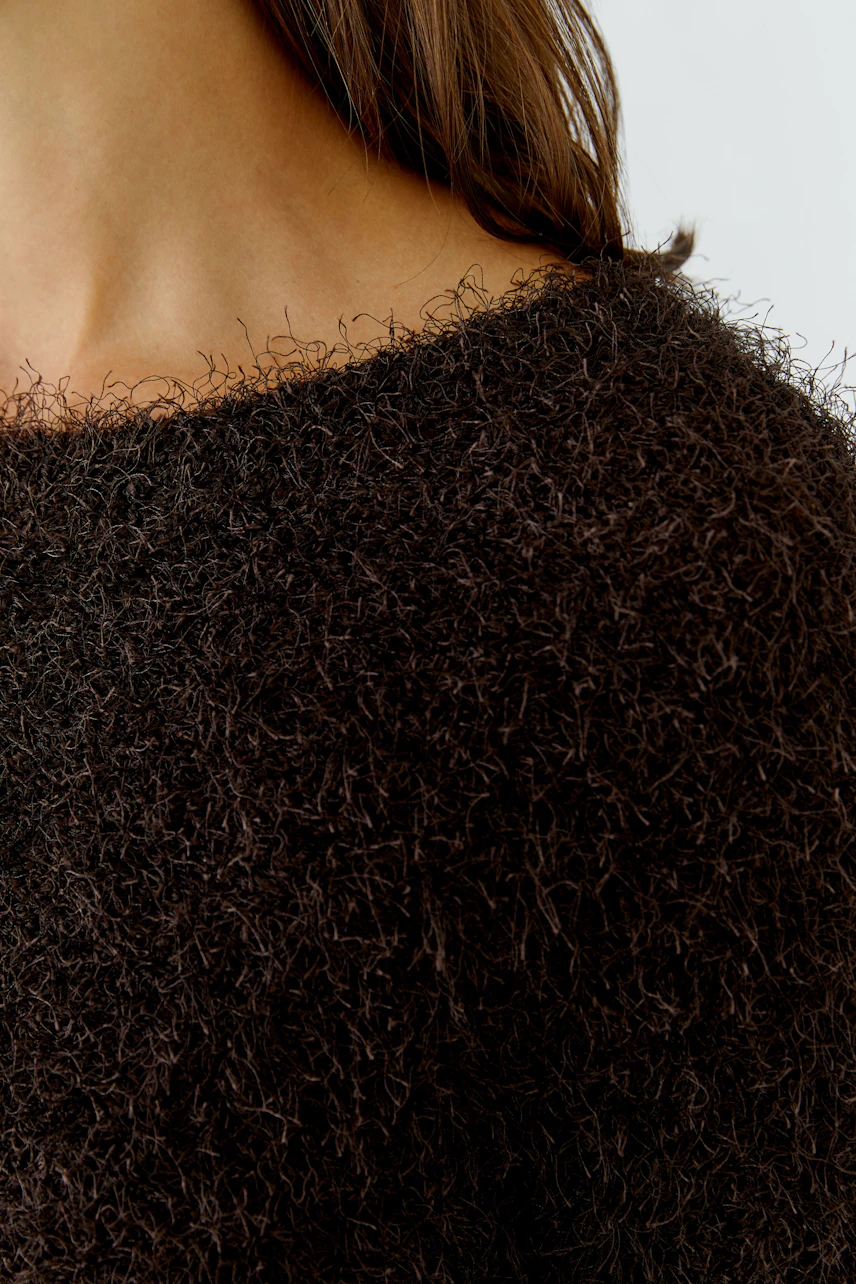Flauschiger Damen-Pullover: Frau trägt braunen, texturierten Pullover mit weitem Ausschnitt.