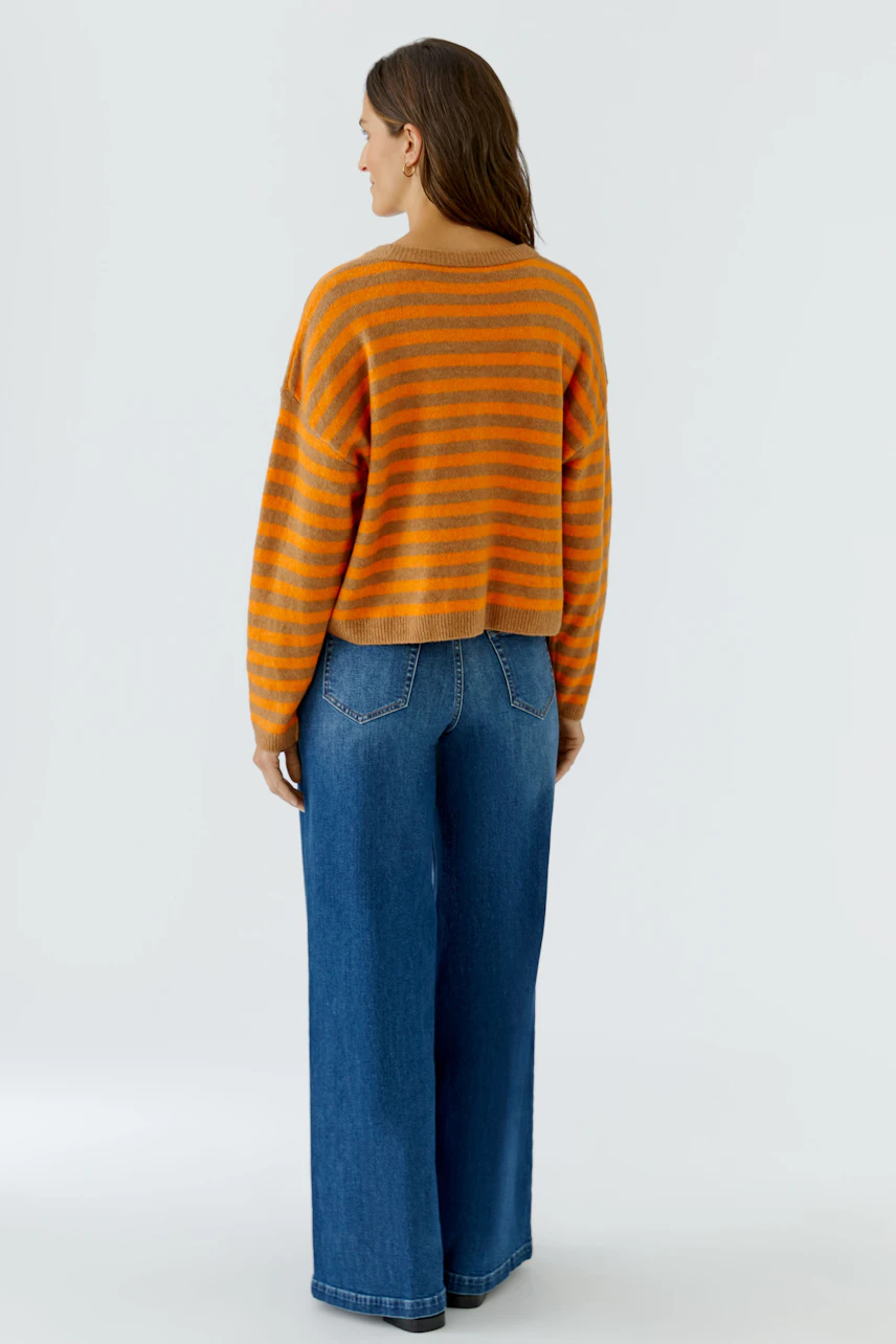 Lässiger Damen-Pullover: Frau im gestreiften Pullover in Orange und Grau, kombiniert mit blauer Jeans.