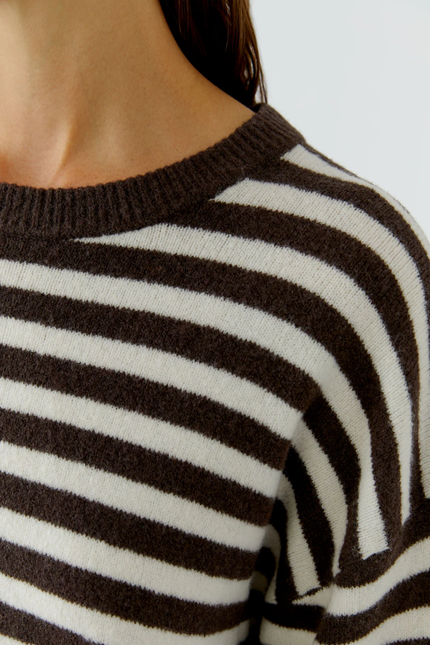 Gestreifter Damen-Pullover: Frau trägt lässigen Pullover mit braunen und weißen Streifen.