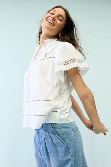White blouse with lace details and short sleeves, perfect for a casual and stylish look.