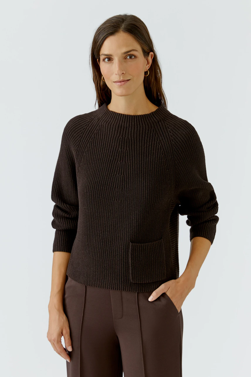 Damen-Pullover: Frau im braunen Strickpullover mit Rundhalsausschnitt und aufgesetzter Tasche.