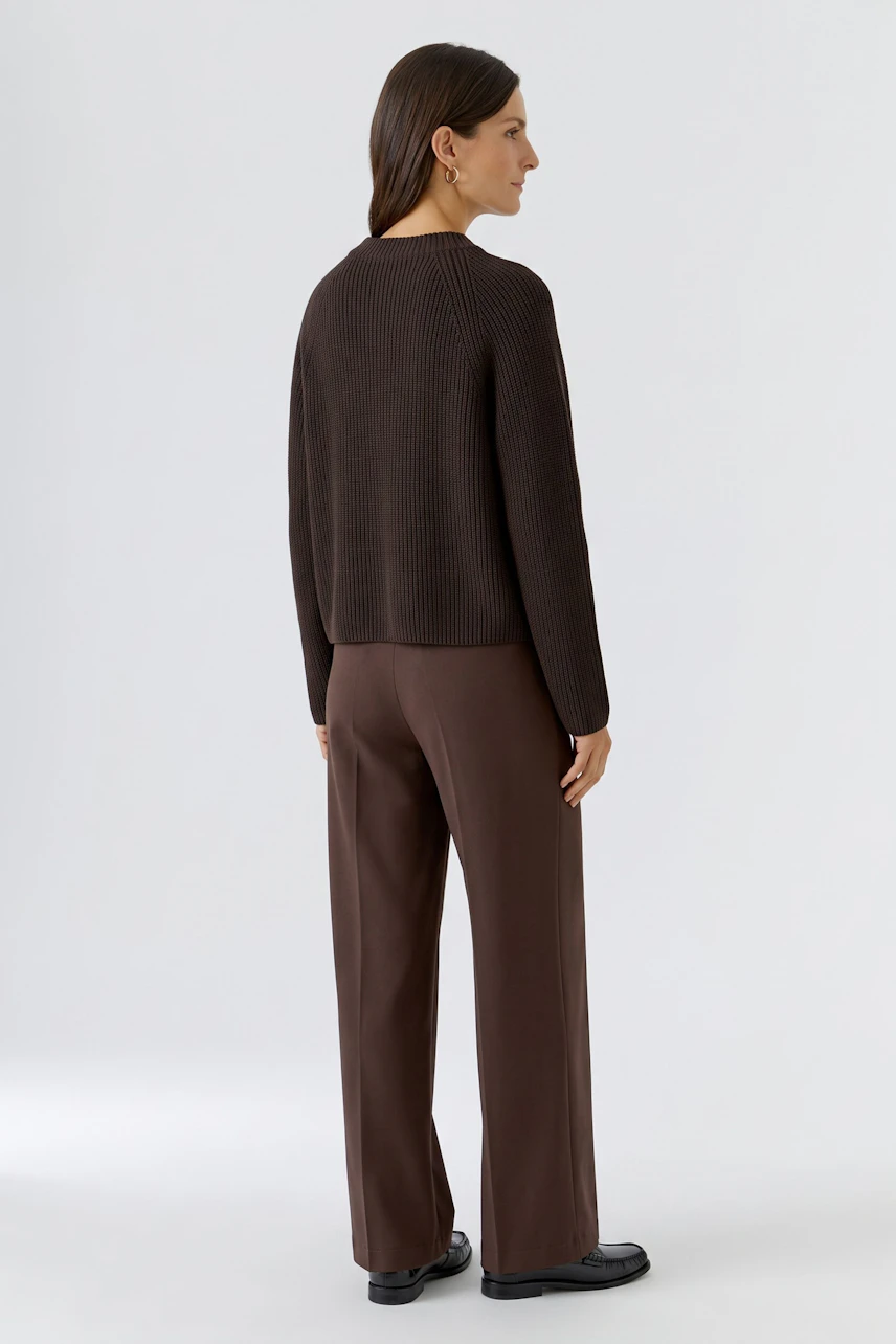Damen-Pullover: Frau im braunen Pullover und passender Hose, von hinten gesehen.