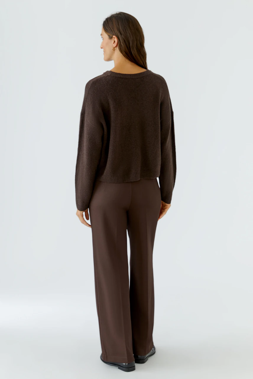 Damen-Pullover: Frau im braunen Pullover und passender Hose von hinten, schlicht und bequem.