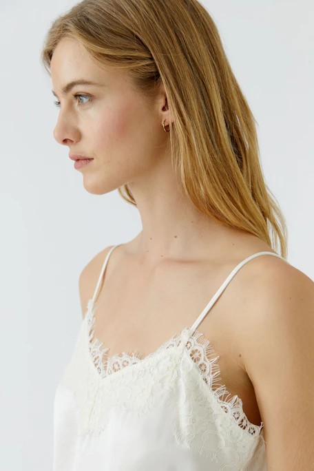 Weißes Damen-Top mit Spitze: Asymmetrischer Saum, zarte Träger, ideal für sommerliche Outfits.