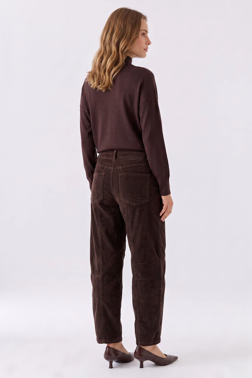 Damen-Hose: Frau in brauner Cordhose und passendem Pullover, seitlich stehend, mit lockigem Haar.