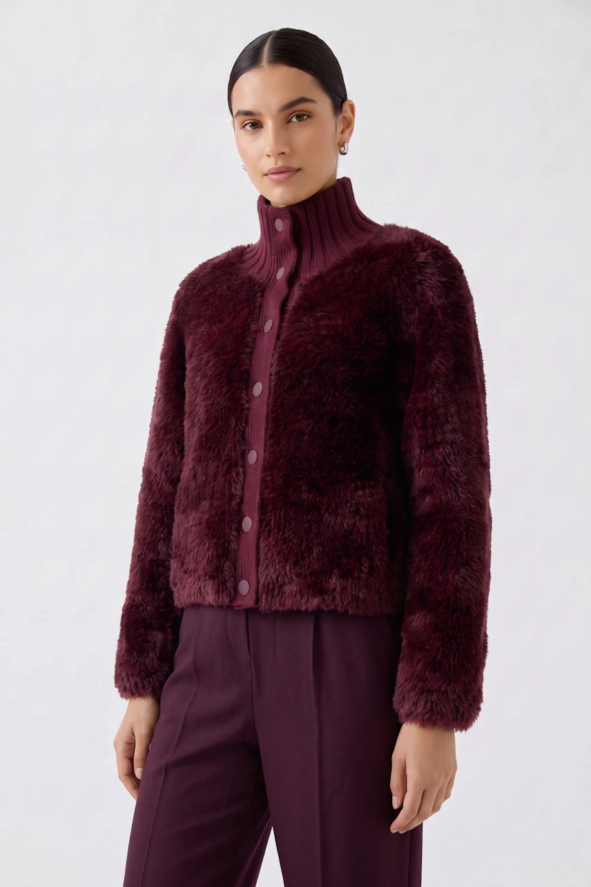 Woman in a burgundy cardigan with a high collar, buttoned front, and matching pants, exuding confidence.
