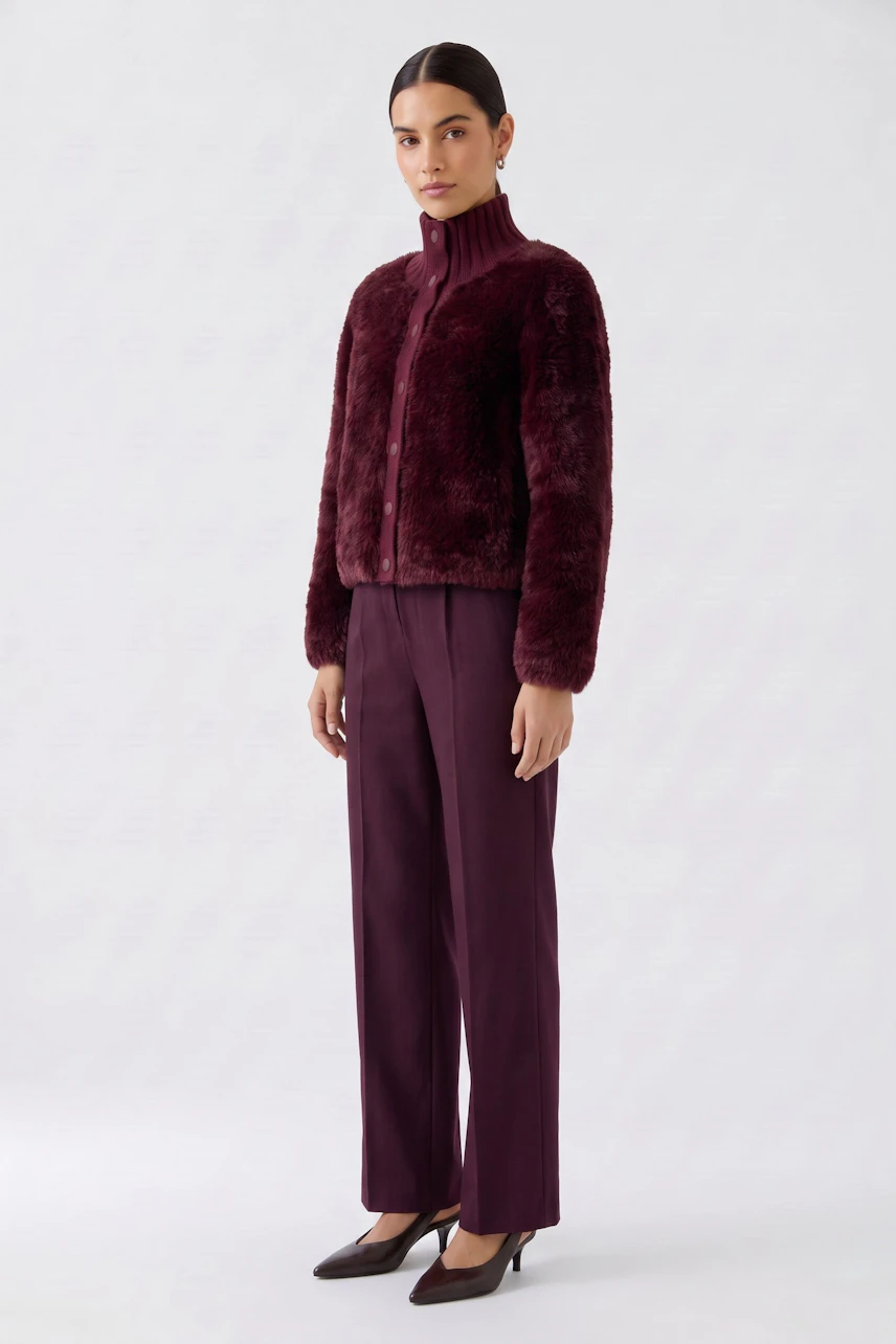 Woman in a burgundy cardigan and matching pants, standing confidently. Cozy and stylish knitwear.
