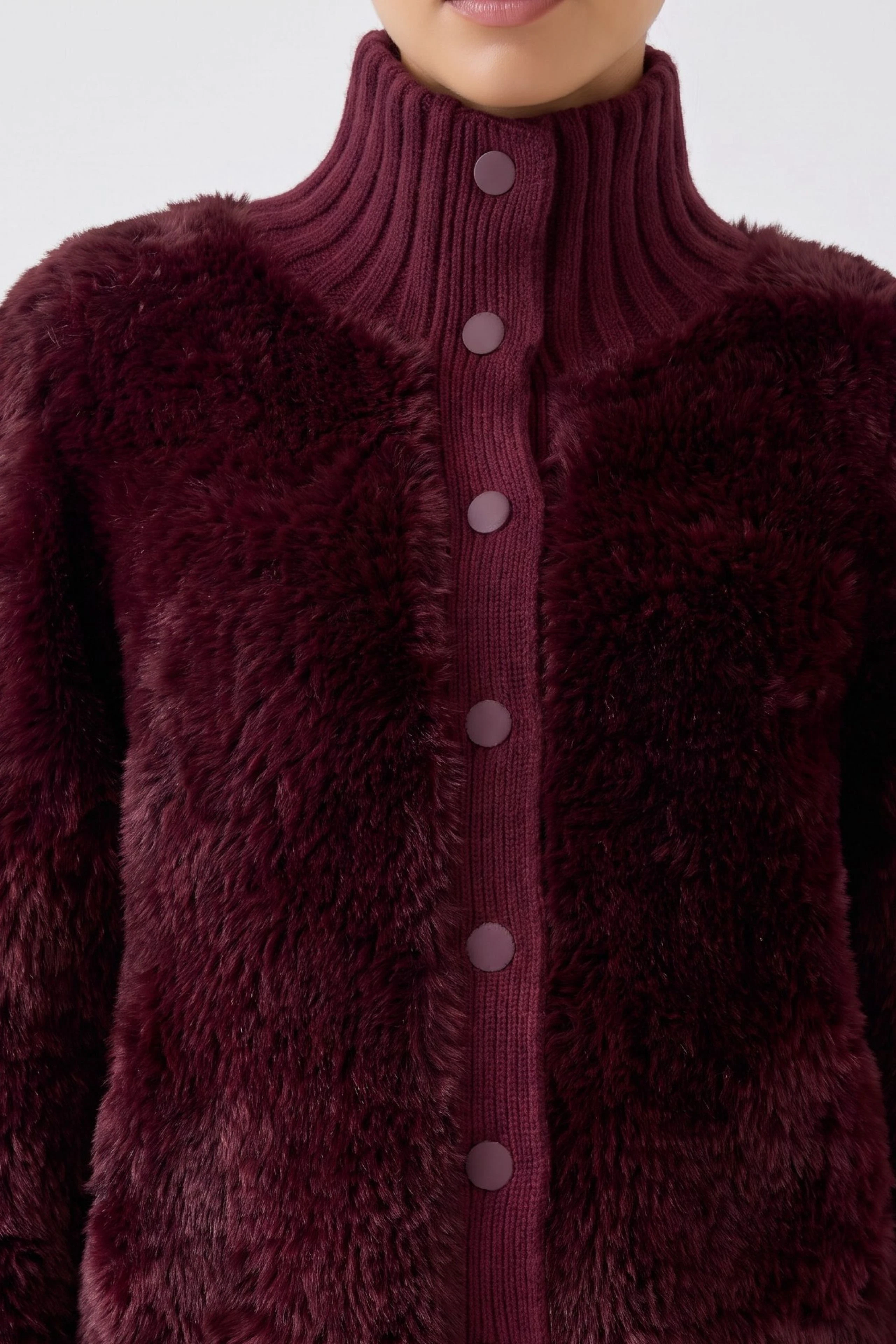 Flauschige Strickjacke: Frau in weinroter Strickjacke mit hohem Kragen und Knopfleiste, warm und stilvoll.