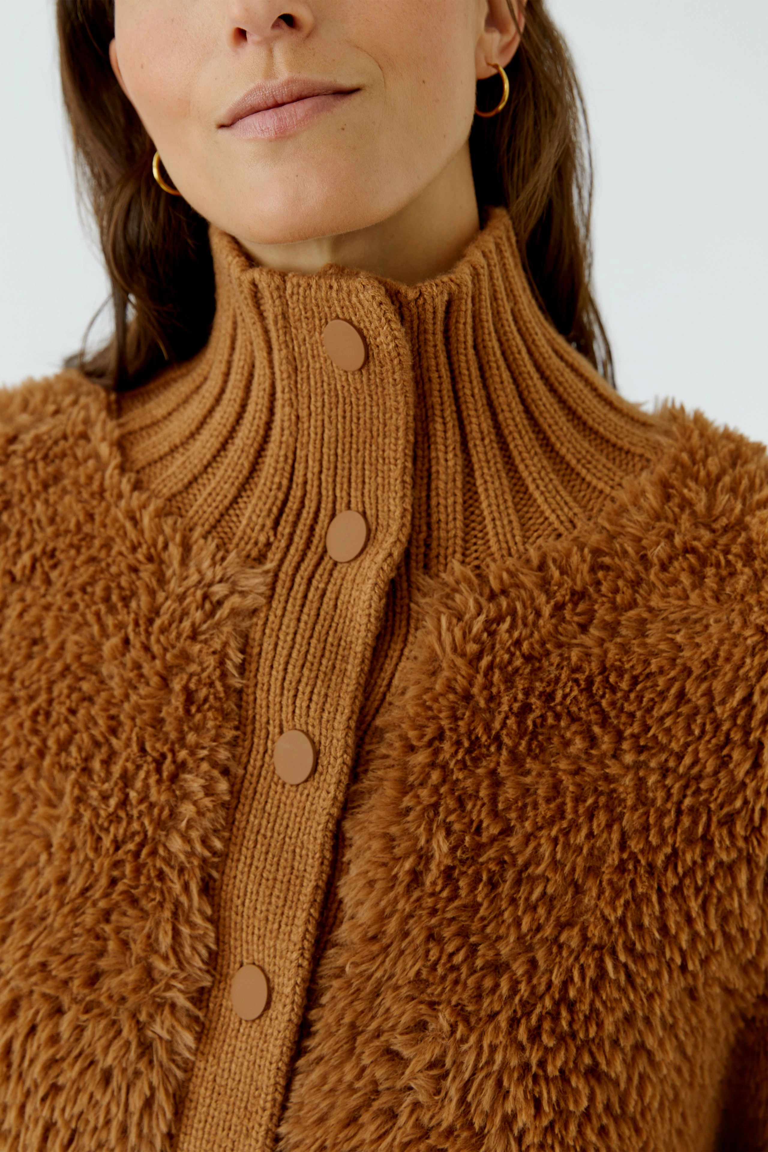 Woman in cozy brown cardigan with ribbed collar and button details, exuding warmth and comfort.