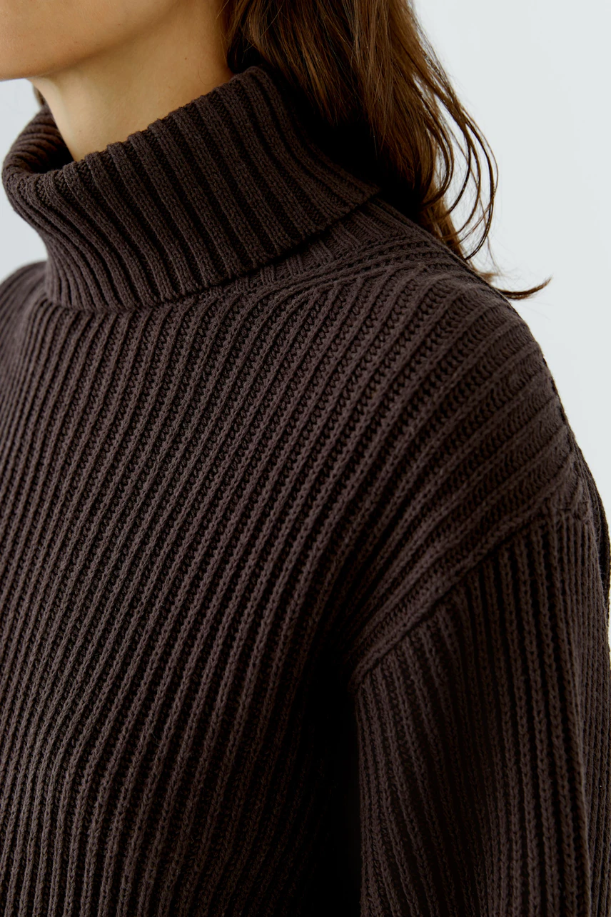 Woman in a ribbed turtleneck pullover, showcasing cozy texture and casual style.