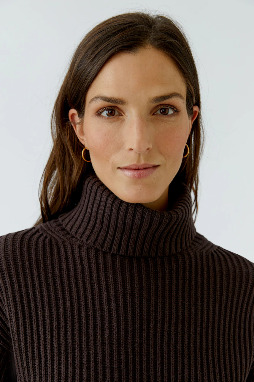 Woman in a ribbed turtleneck pullover, showcasing a casual and confident style.