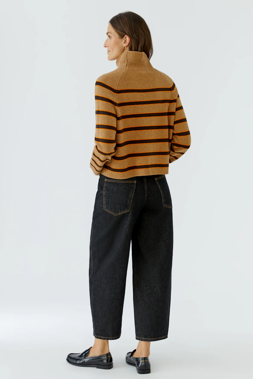 Gestreifter Damen-Pullover: Frau im braunen Pullover mit Rollkragen und weiten Jeans, lässig und modern.
