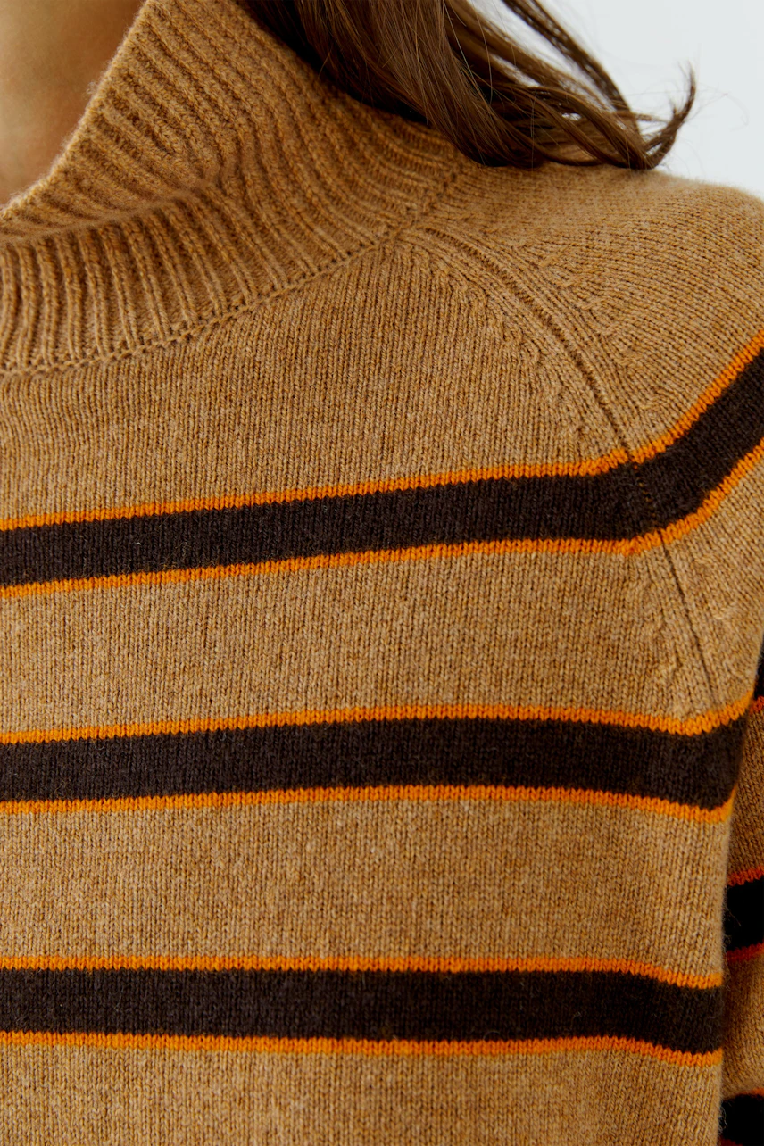 Gestreifter Damen-Pullover: Frau trägt braunen Pullover mit orange-schwarzen Streifen und hohem Kragen.