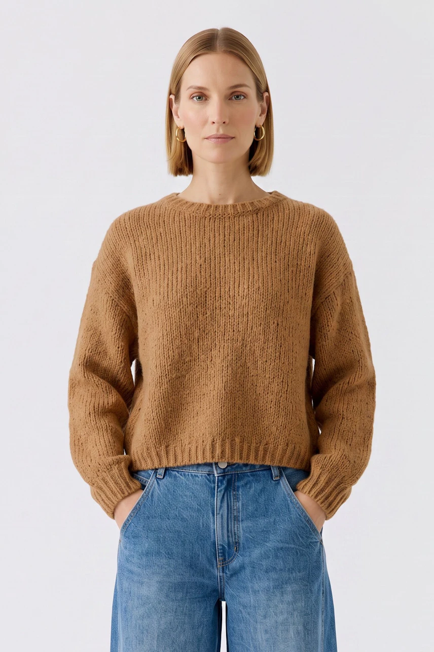 Lässiger Damen-Pullover: Frau im braunen Strickpullover mit blauen Jeans, entspannt und modern.