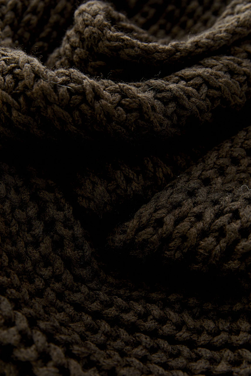 Cozy knitted scarf in dark brown, showcasing thick, textured yarn for warmth and style.