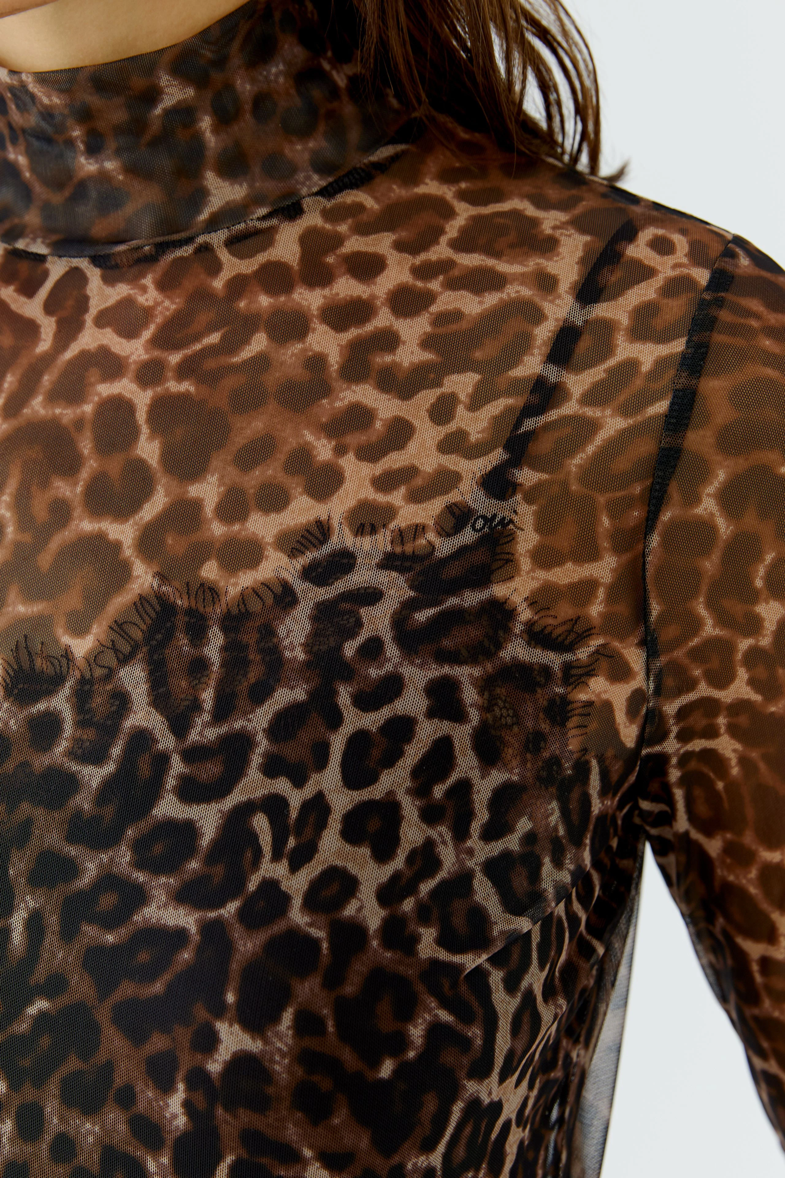 Women's long-sleeve shirt: Sheer leopard print with high neck, worn by a woman, showcasing bold style.