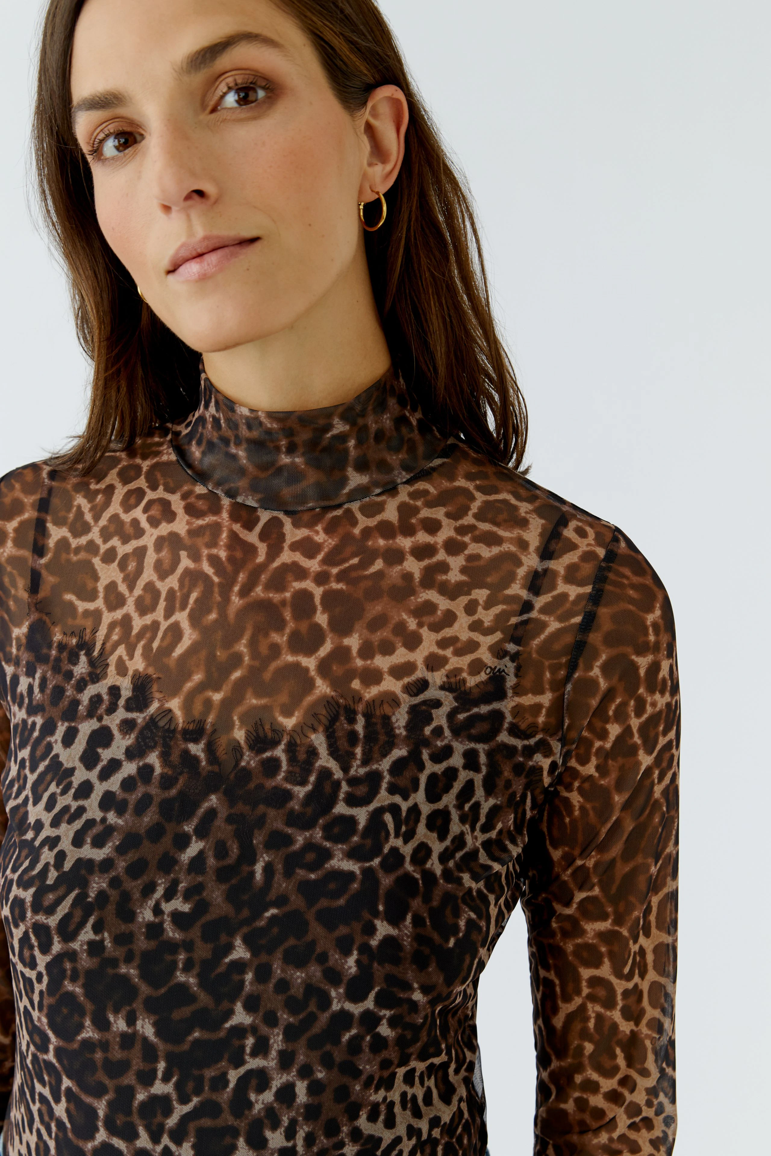 Woman in leopard print long-sleeve shirt, looking confidently. Perfect for a bold, stylish look.