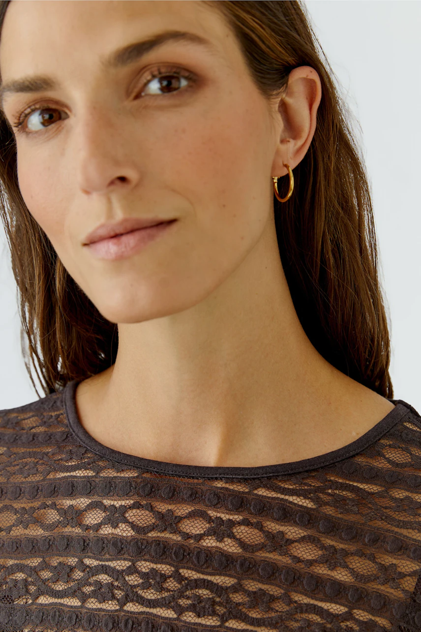 Frau im Langarmshirt aus Spitze: Dezentes Design, ideal für vielseitige Kombinationen.