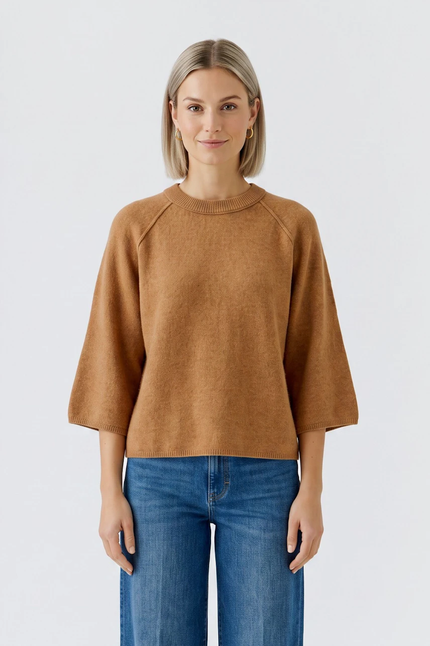 Lässiger Damen-Pullover: Frau im braunen Pullover mit 3/4-Ärmeln und blauen Jeans lächelt freundlich.