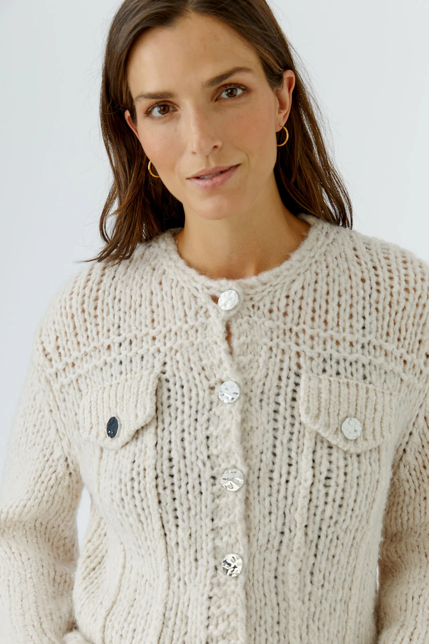 Woman in cozy knit cardigan with button details, soft texture, and front pockets, exuding casual style.