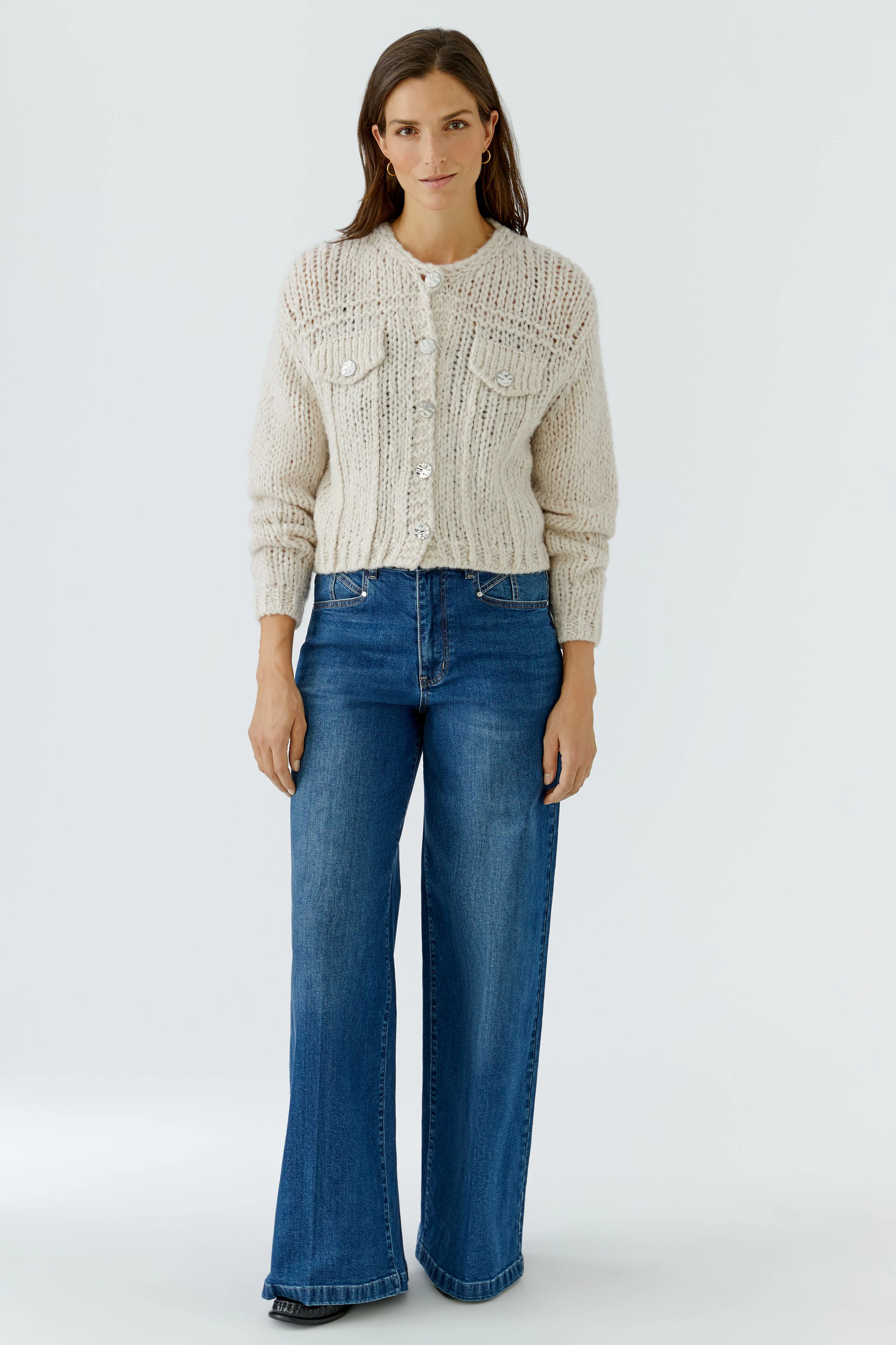 Cremefarbene Strickjacke: Weiche, grob gestrickte Jacke mit Knopfleiste und Brusttaschen.