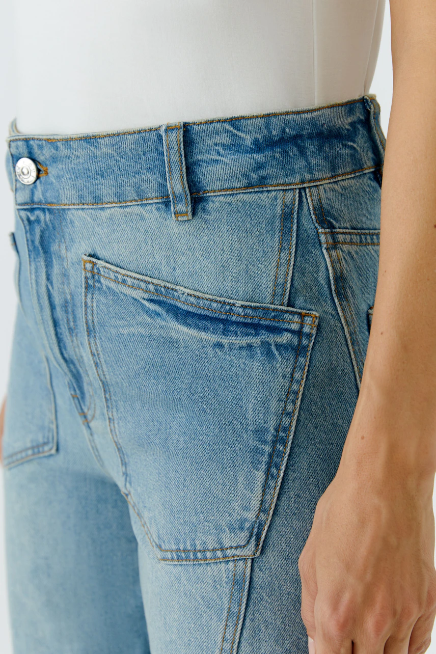 Damen-Culotte in Denim: Frau trägt lässige Jeans-Culotte mit hohem Bund und großen Taschen.