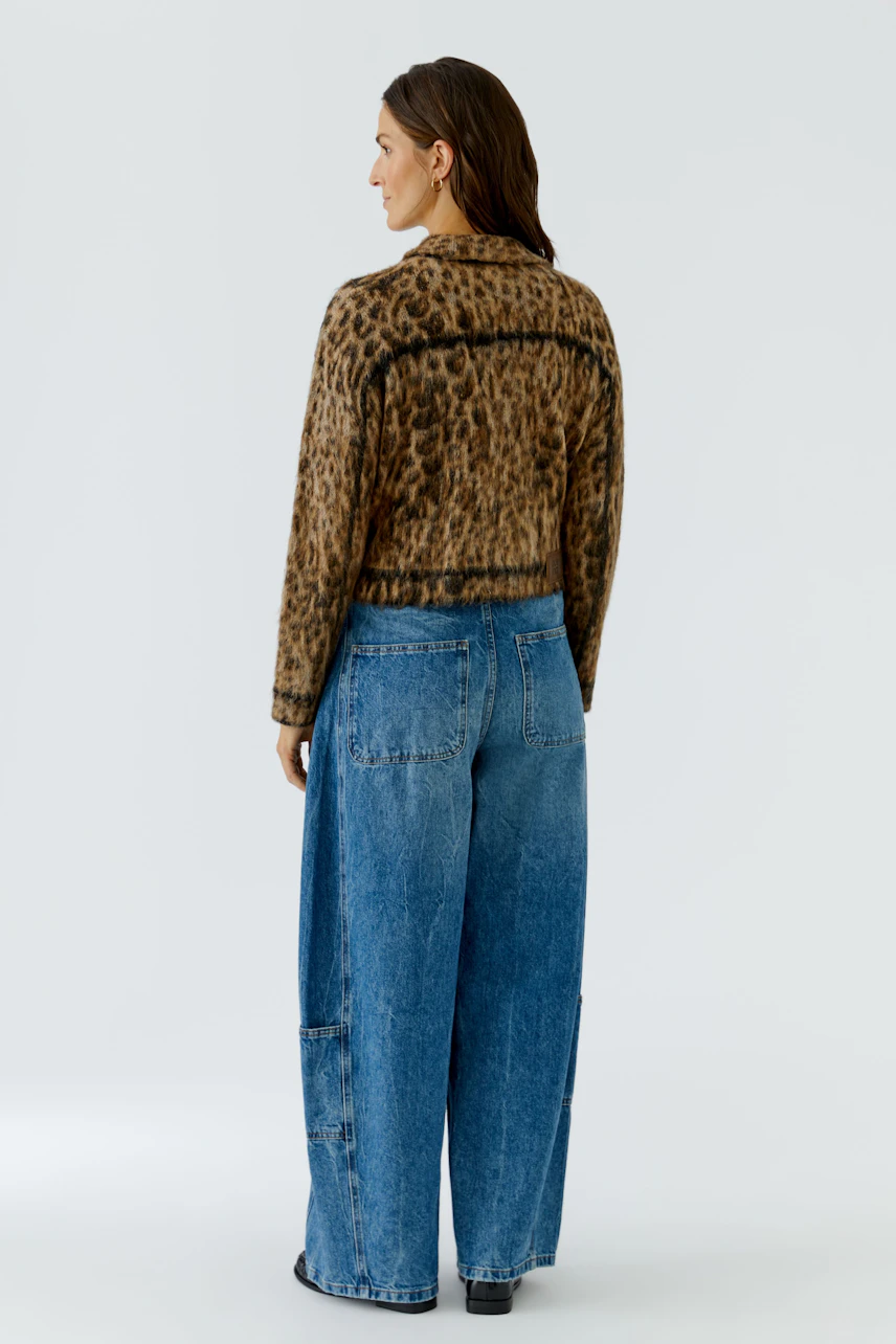 Strickjacke mit Leopardenmuster: Frau in lässiger Jeans und Strickjacke von hinten.