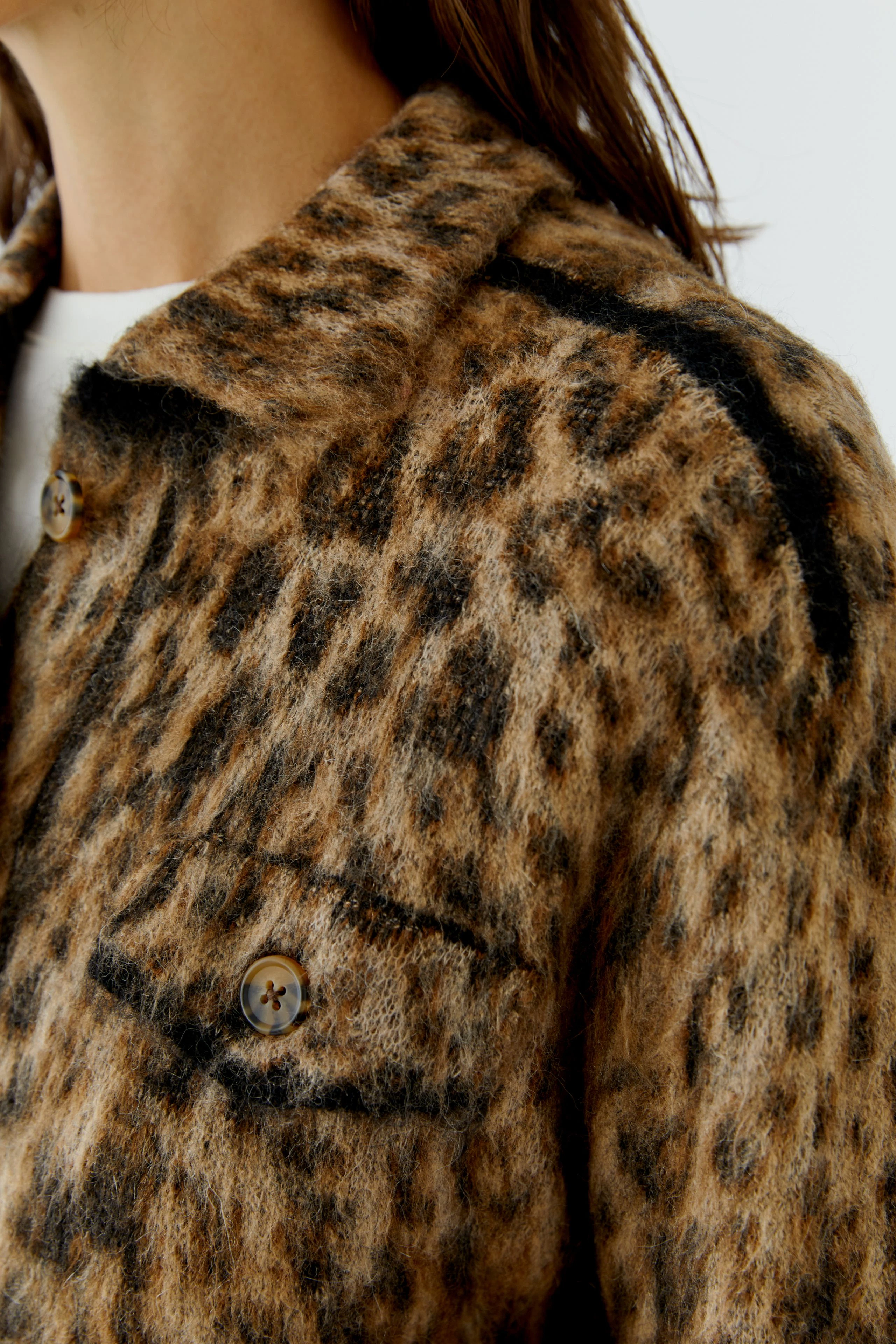 Leopard print cardigan: Woman in a cozy, button-up cardigan with bold animal pattern, exuding casual style.