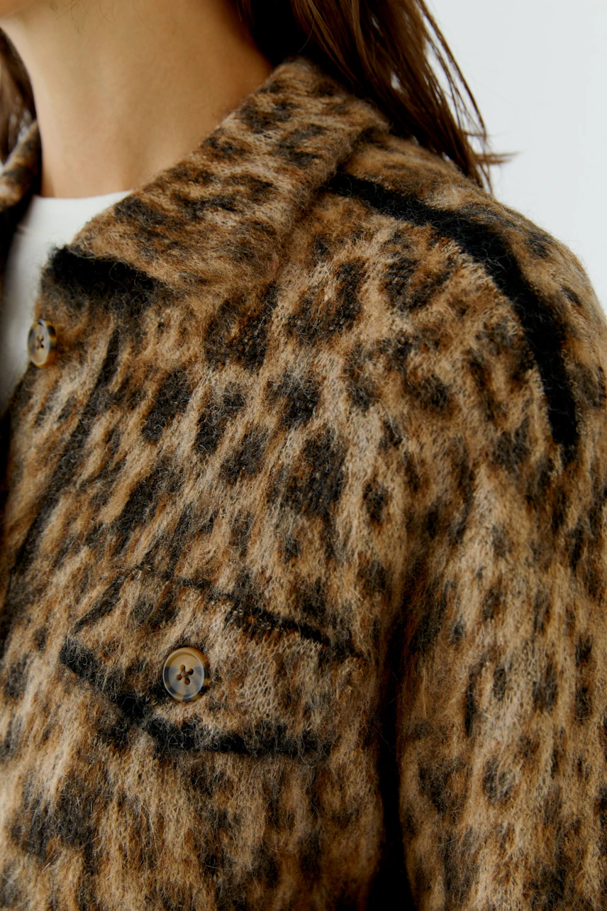Strickjacke mit Leopardenmuster: Frau trägt flauschige Jacke mit Knöpfen, wildes Design für modischen Look.