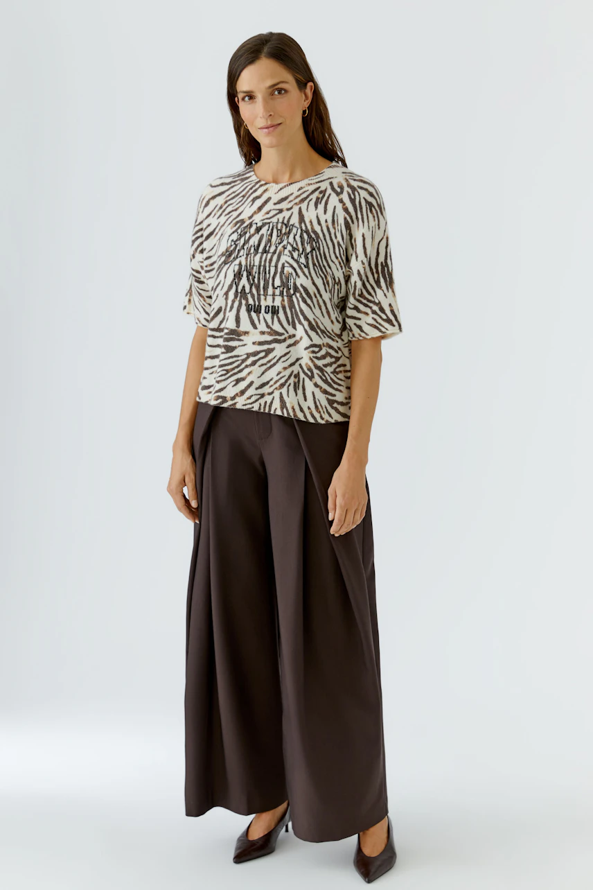 Damen-Pullover: Frau im gemusterten Pullover mit kurzen Ärmeln und weiter Hose, lässiger Look.