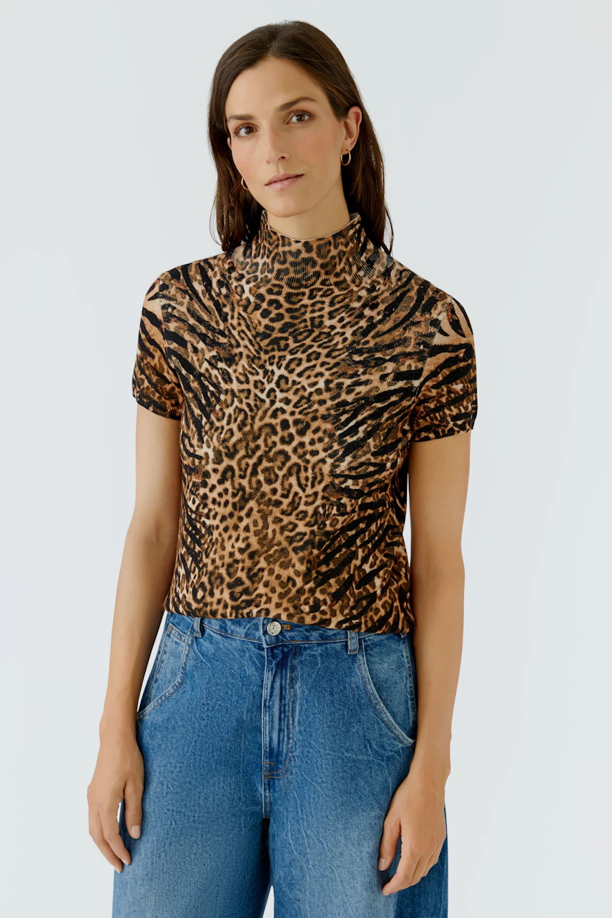 Damen-Pullover: Frau im kurzärmeligen Leoparden-Pullover, kombiniert mit blauen Jeans, schaut direkt.