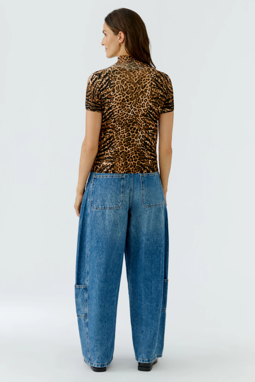 Lässiger Damen-Pullover: Frau im Leopardenmuster-Pullover und weiten Jeans, von hinten gesehen.
