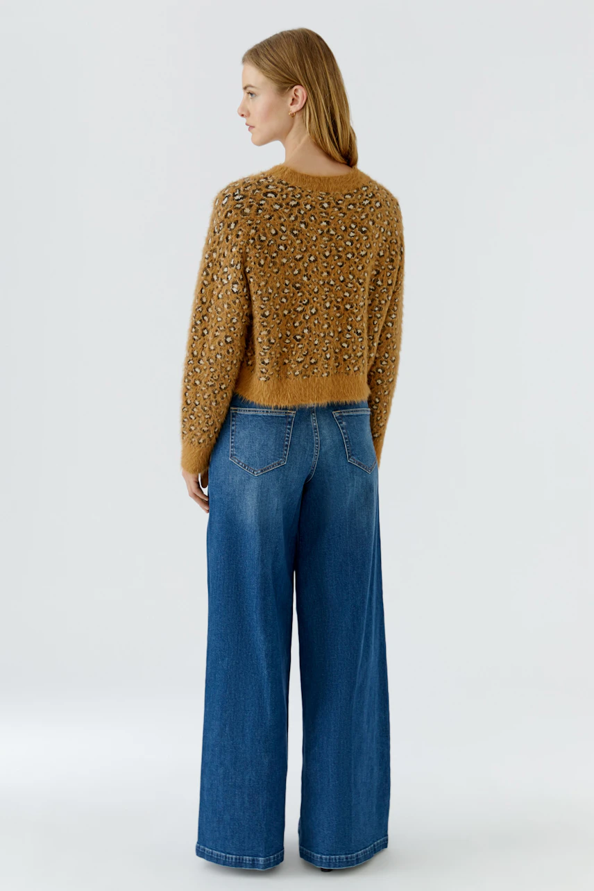 Lässiger Damen-Pullover: Frau im gemusterten Pullover und blauer Jeans von hinten gesehen.