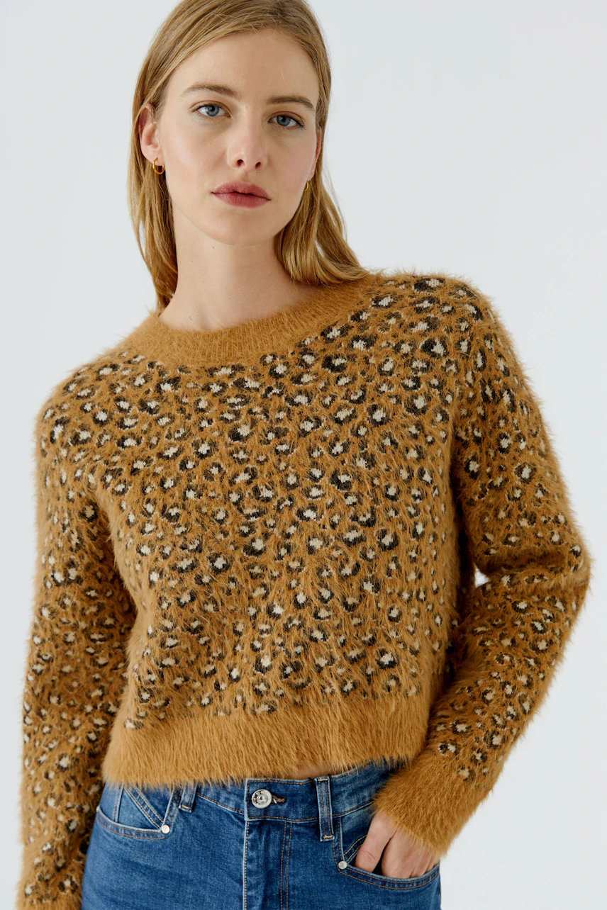 Damen-Pullover: Frau im flauschigen, gemusterten Pullover in Braun mit Leopardenmuster und blauer Jeans.