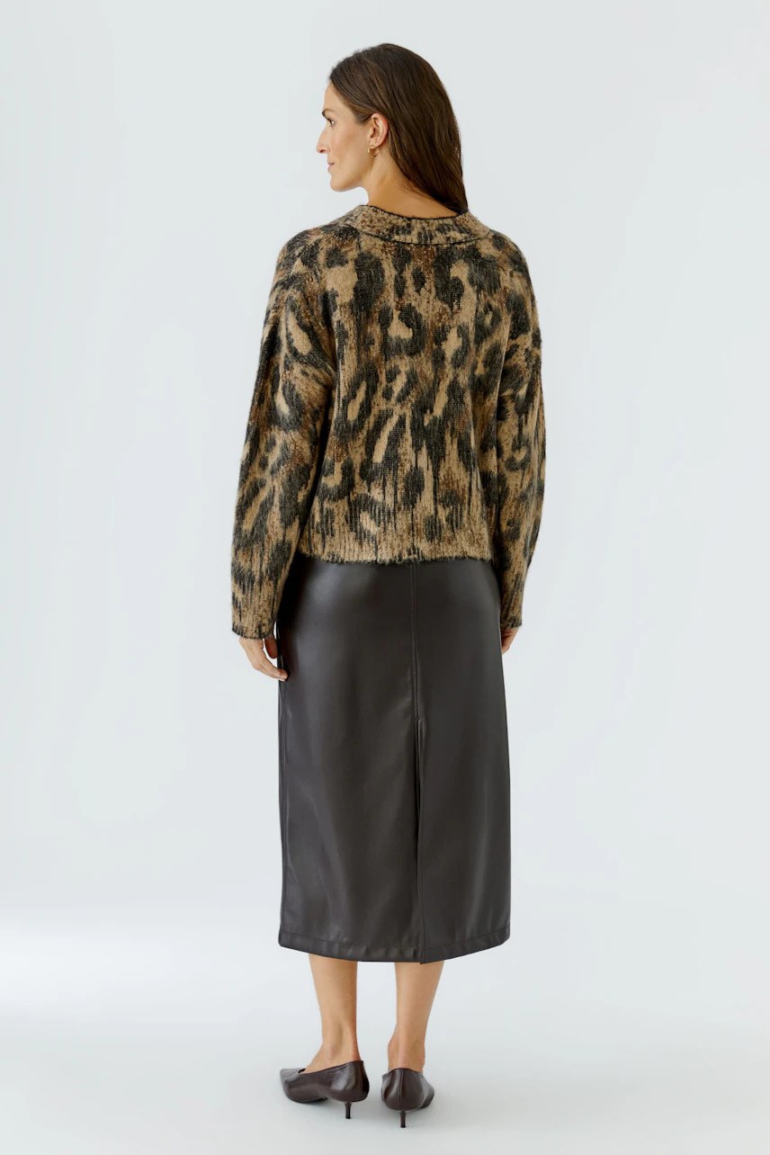 Damen-Pullover: Frau im gemusterten Pullover und schwarzem Rock von hinten, schlicht und modern.