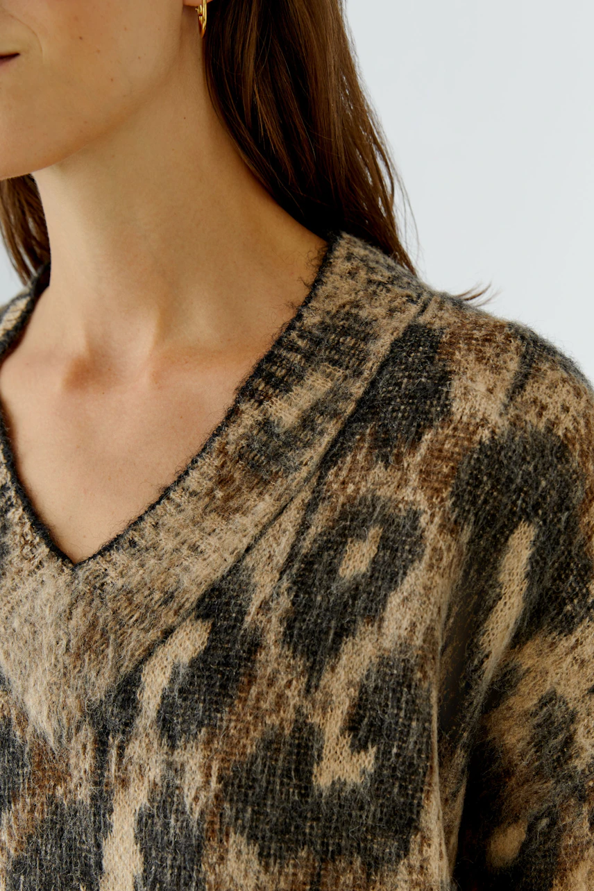 Damen-Pullover: Frau trägt gemusterten V-Pullover in Braun- und Beigetönen, lässig und modern.