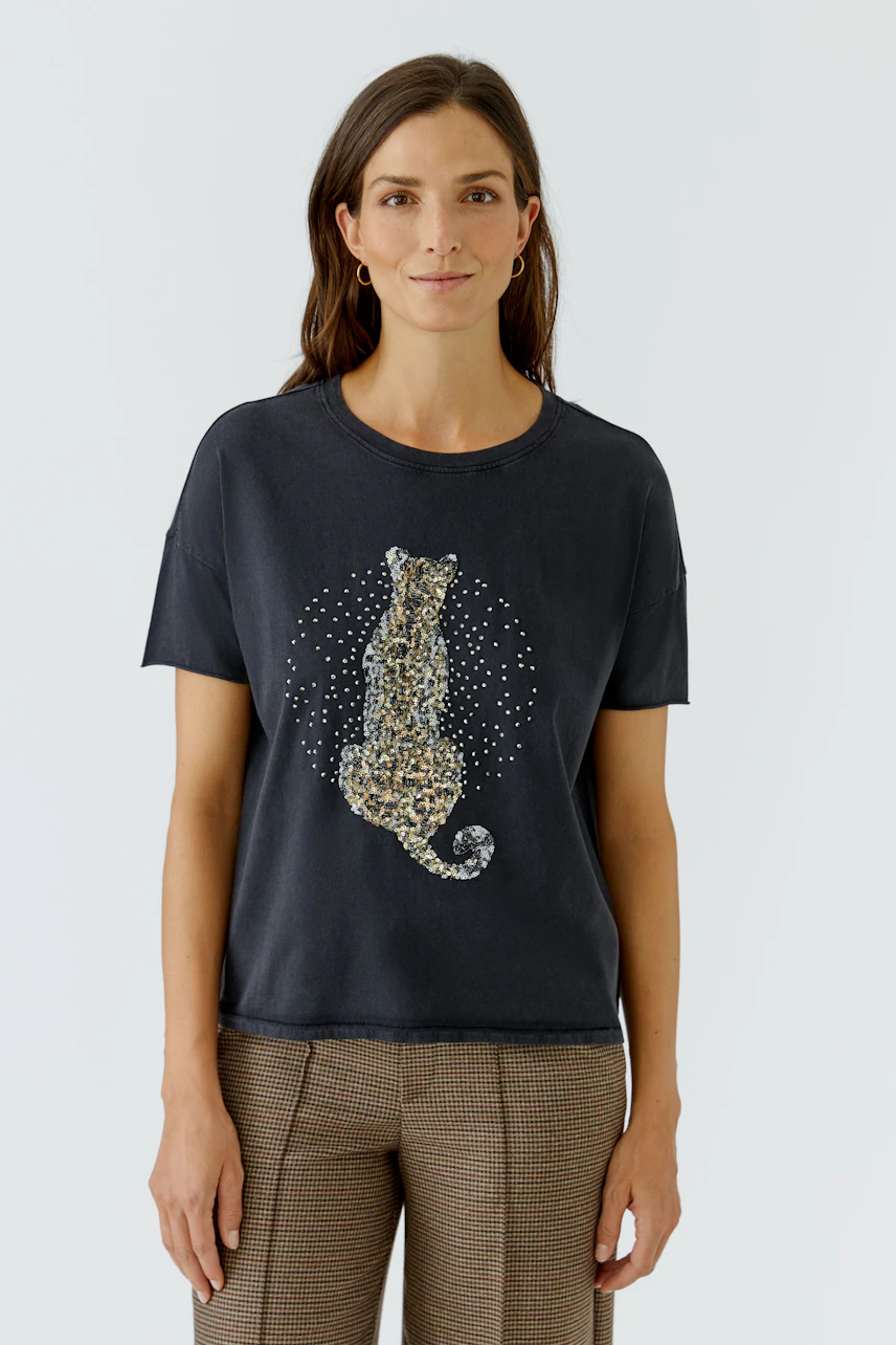 Casual women's T-shirt: Woman in a black T-shirt with a leopard print, paired with checkered pants.