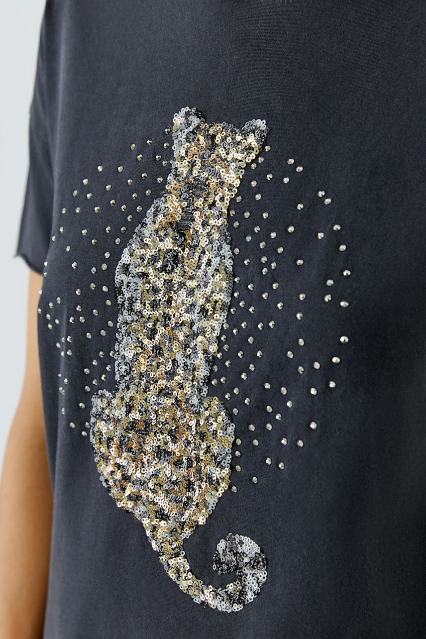 Women's T-shirt: Black T-shirt with a sequined leopard design, worn by a woman.