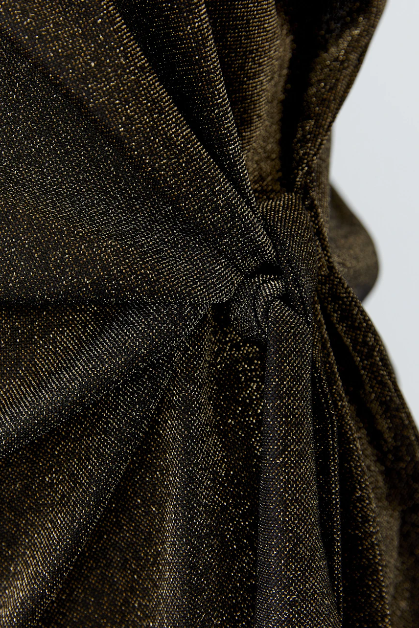 Close-up of a textured T-shirt with a knot detail, showcasing shimmering fabric in a dark hue.