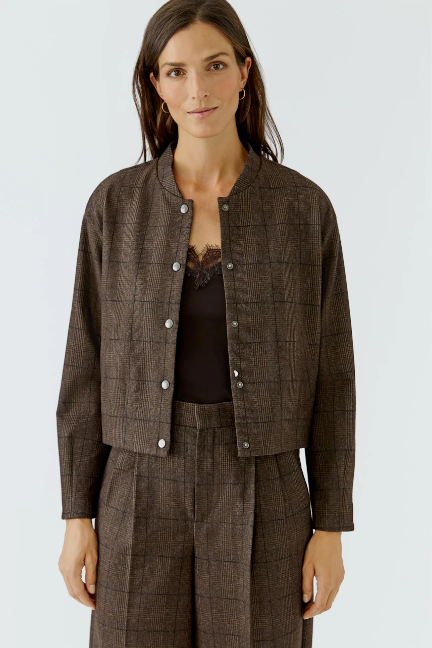 Casual women's jacket: Woman in a brown checkered jacket with button closure, paired with matching pants.
