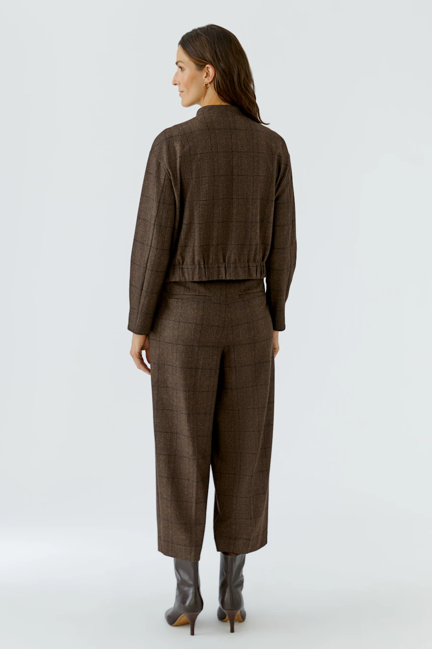 Casual women's jacket: Woman in a brown checkered jacket and matching pants, standing confidently.