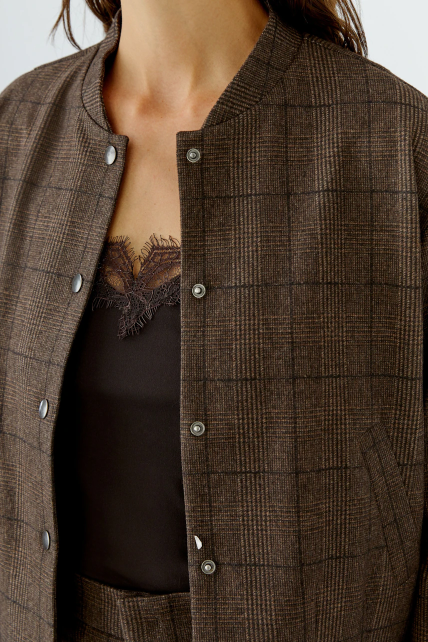 Casual women's jacket: Woman in a brown checkered jacket over a lace-trimmed top.