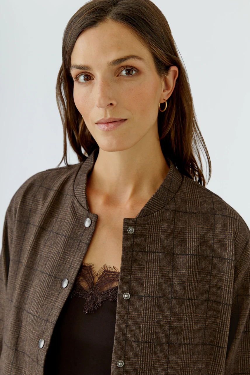 Casual women's jacket: Woman in a brown checkered jacket with a simple black top underneath.