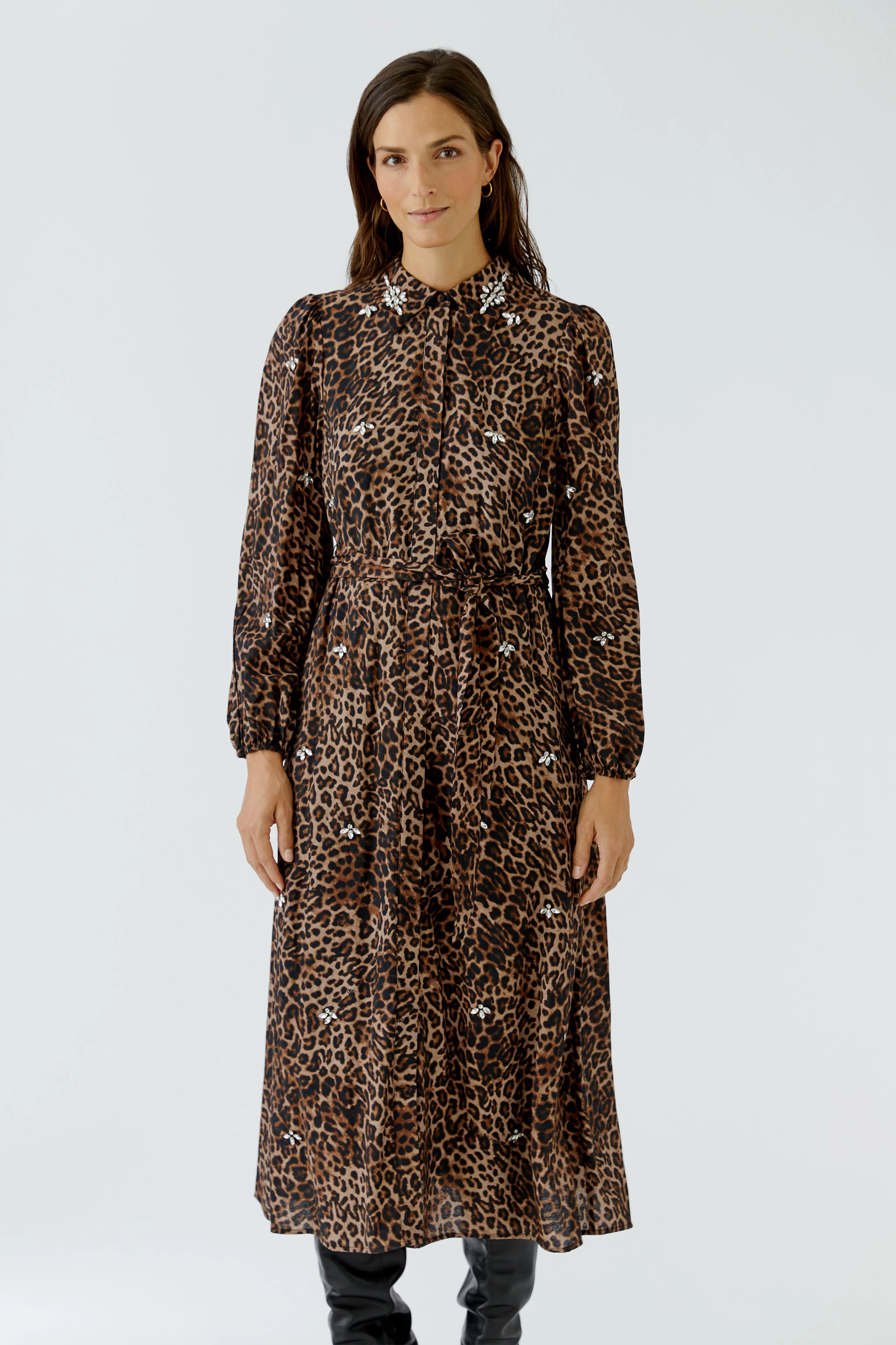 Leopard print maxi dress: Woman in a long-sleeve, button-up dress with a tie waist, standing confidently.