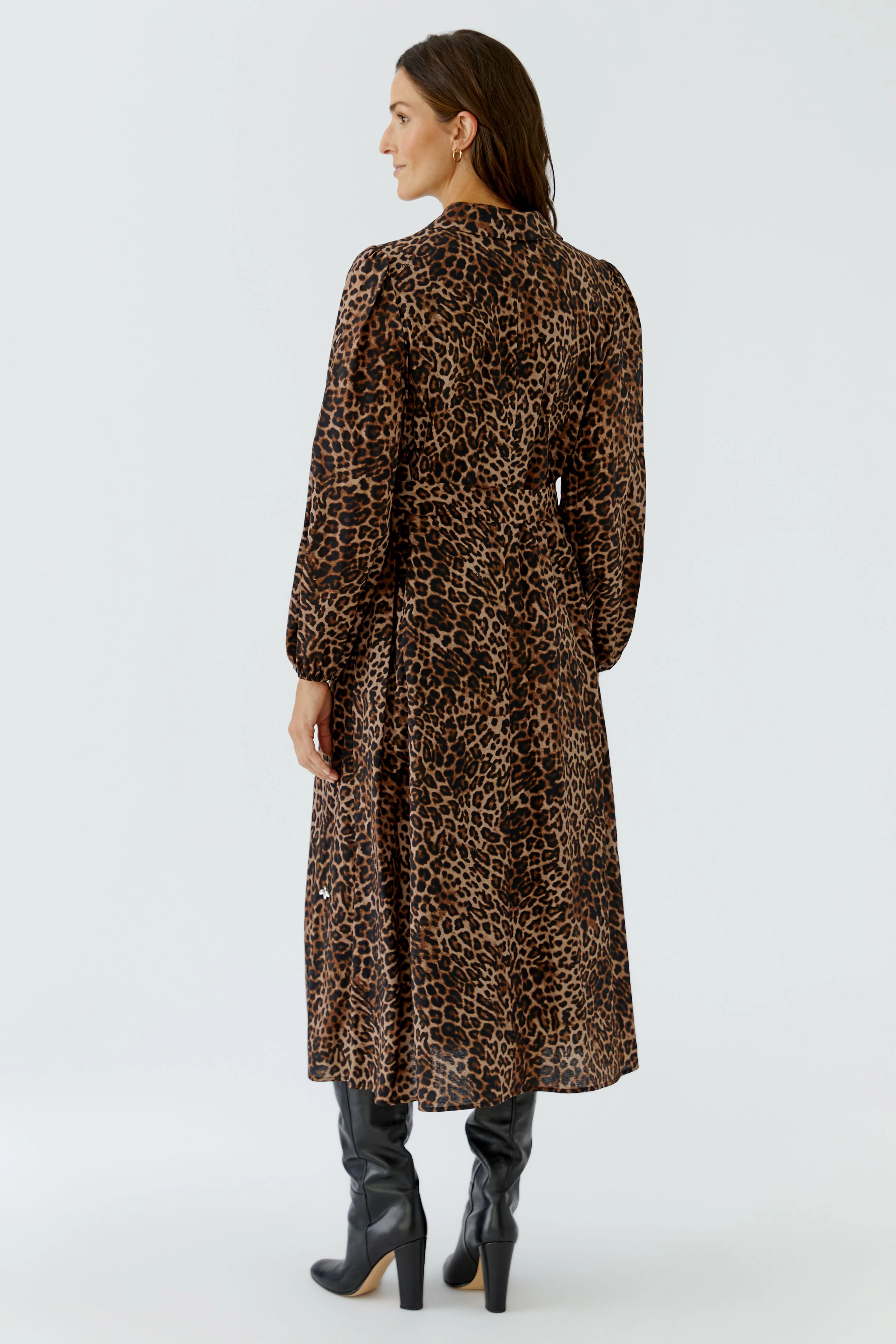 Woman in leopard print maxi dress and black boots, standing confidently.