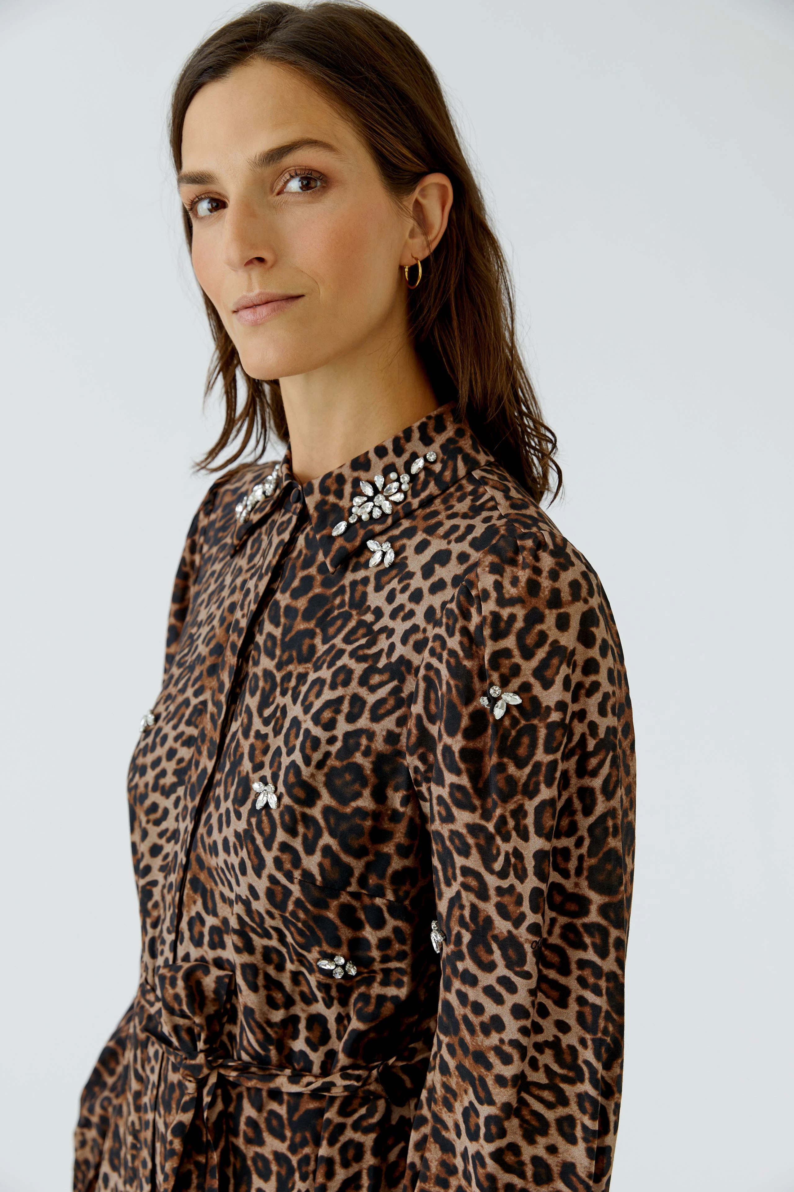 Woman in leopard print maxi dress with embellished collar, looking confidently to the side.